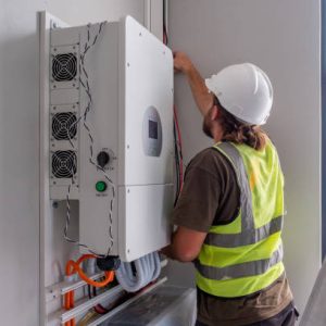 A young male carefully connects and installs a solar inverter system in a residential house. Houses in South Africa installing solar energy solutions